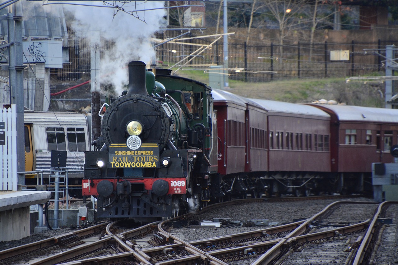 a train traveling down train tracks next to a train station, a portrait, by Peter Prendergast, flickr, brass and steam technology, melbourne, round about to start, working