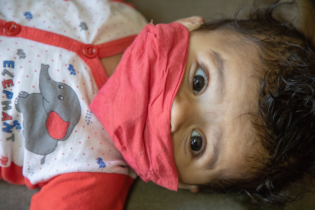 a close up of a child wearing a blindfold, by Judith Gutierrez, conjoined twins, surgical mask covering mouth, hindu, looking down on the camera