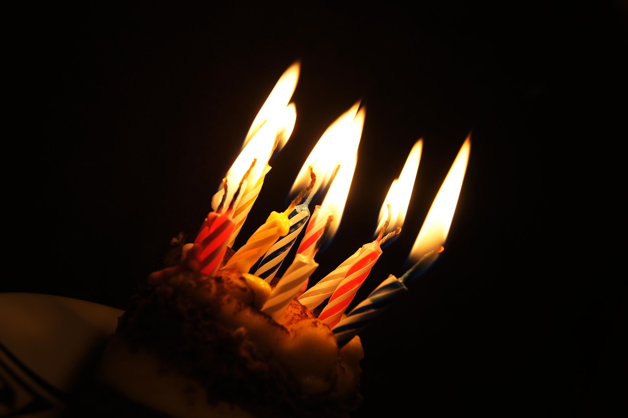 a close up of a piece of cake with lit candles, a picture, by Stefan Gierowski, figuration libre, happy birthday candles, torches, photo taken in 2018, lit from below