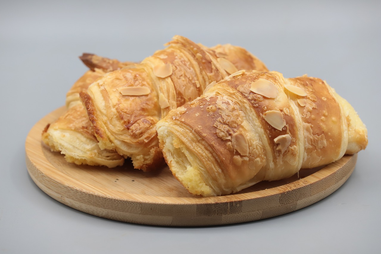 a plate that has some croissants on it, inspired by Normand Baker, hurufiyya, high detail product photo, a wooden, malaysian, high quality product image”