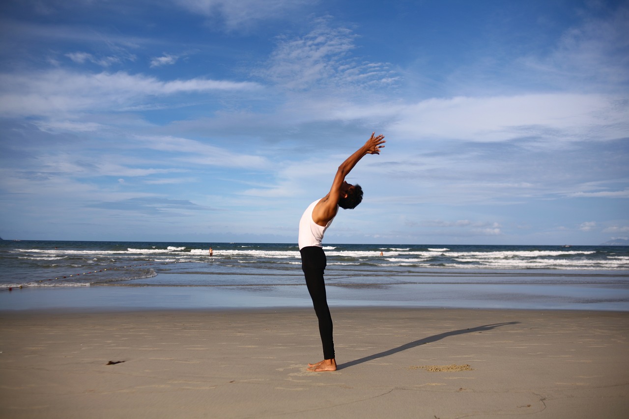 a person doing a yoga pose on the beach, shutterstock, standing posture, fullbody photo