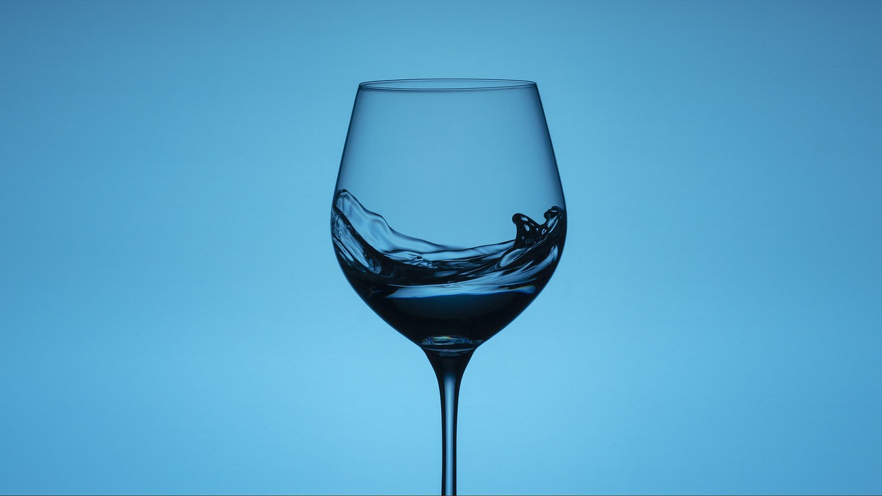 a close up of a wine glass on a table, by Jan Rustem, unsplash, photorealism, azure waves of water, with a blue background, high detail product photo, high resolution product photo