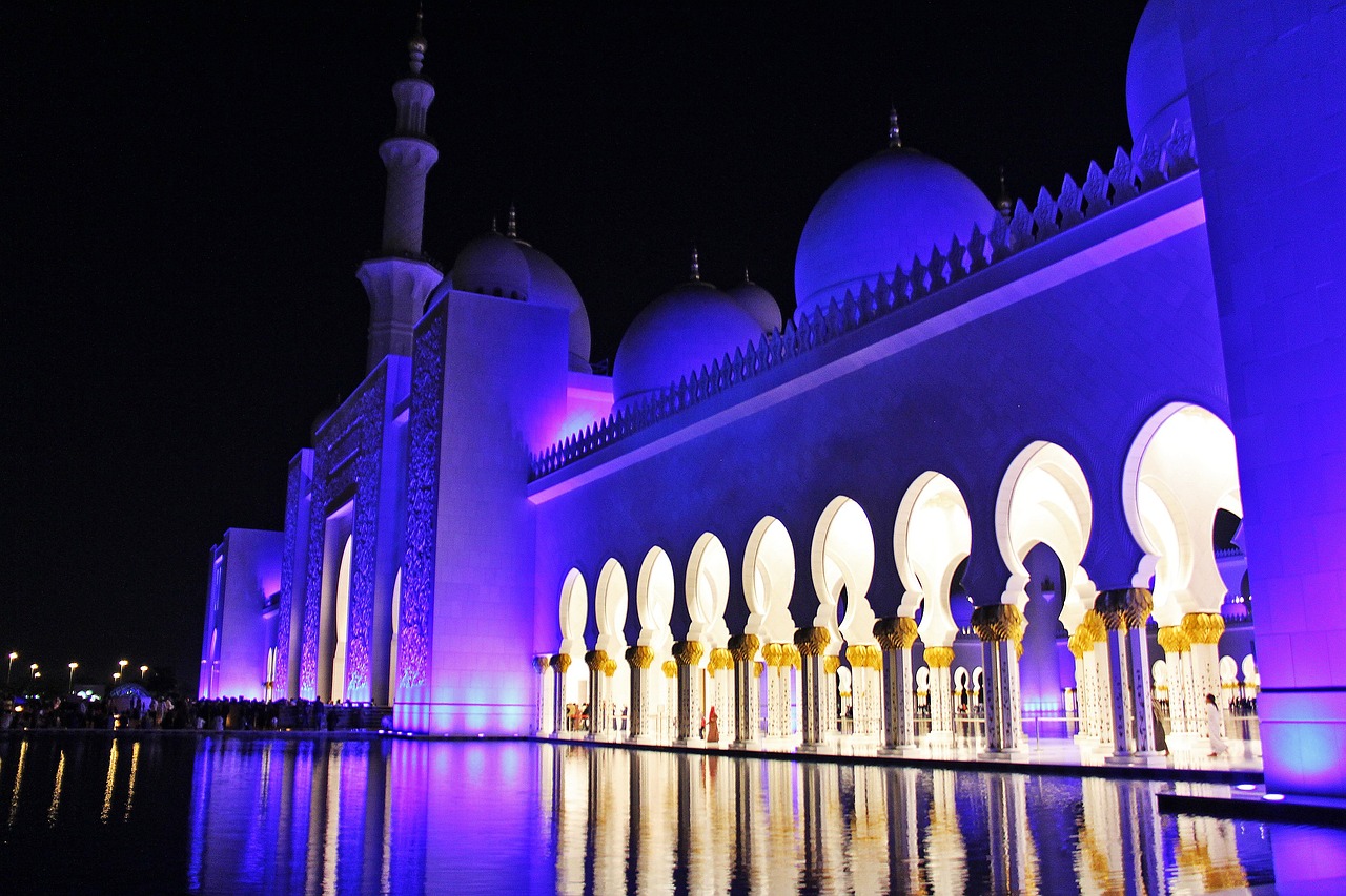 a large white building lit up at night, by Sheikh Hamdullah, pixabay, hurufiyya, blue and purple colour scheme, cybermosque interior, festivals, header