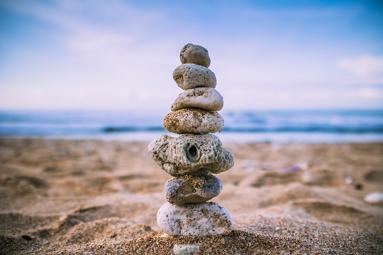 a stack of rocks sitting on top of a sandy beach, a picture, by Alexander Robertson, unsplash, balancing the equation, intricate and complex, 🚀🚀🚀, eye level view