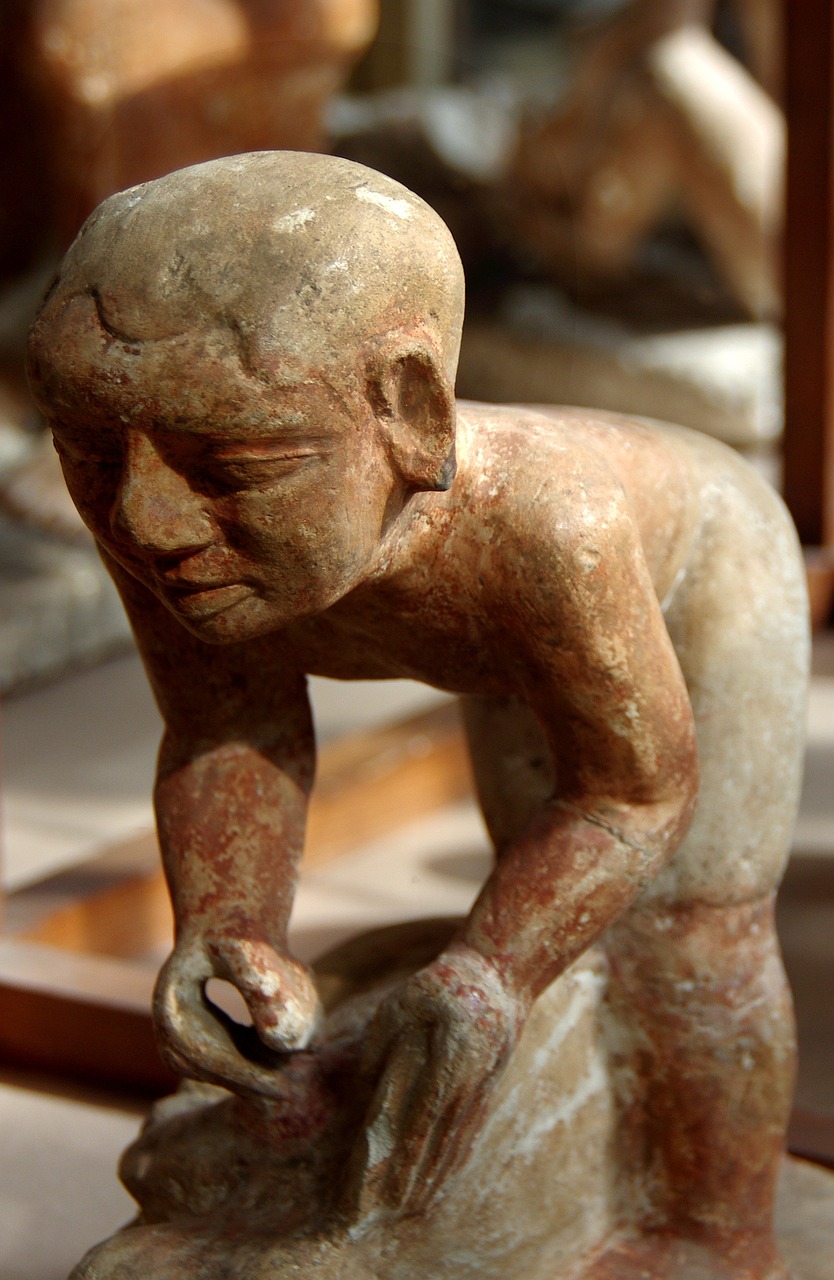 a statue sitting on top of a table next to a mirror, flickr, mingei, young male with walking stick, from egypt, toddler, close up