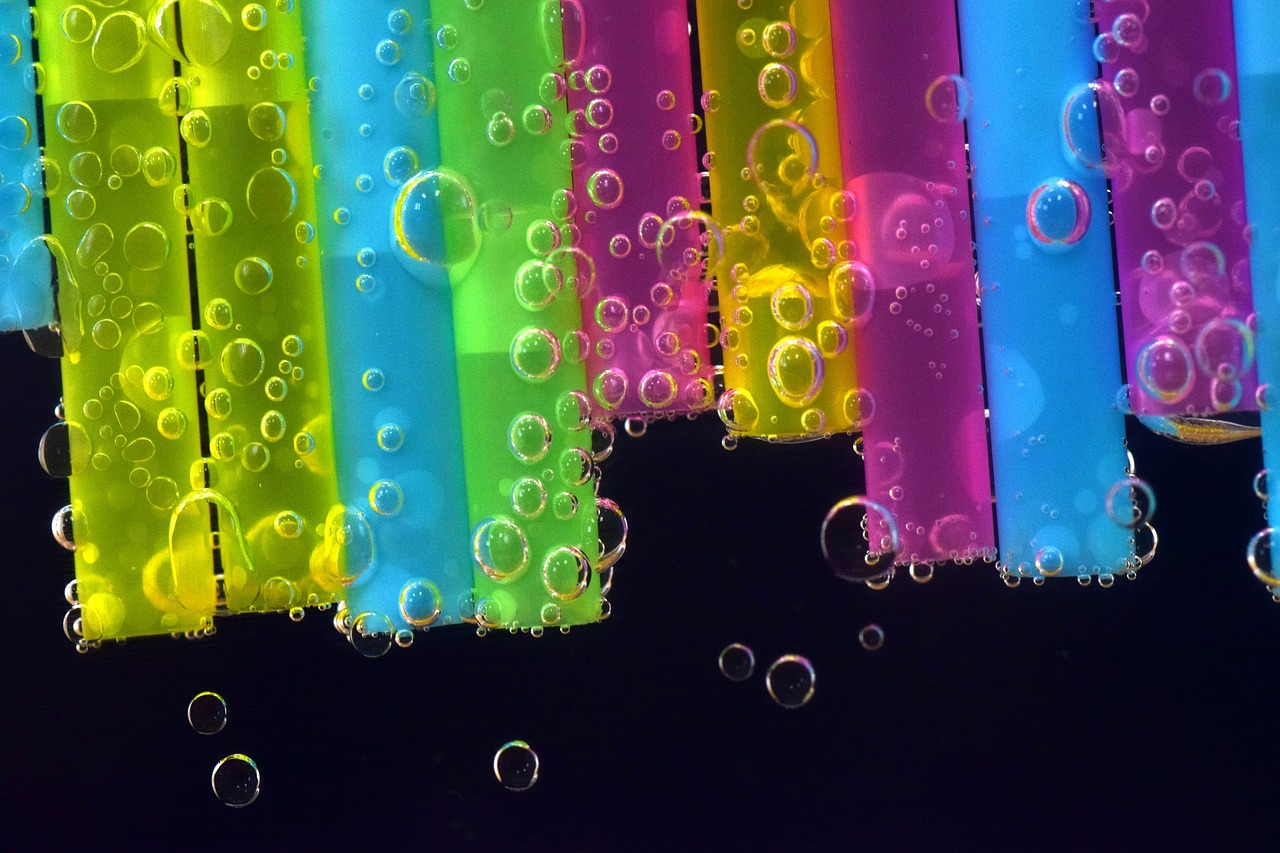 a bunch of bubbles floating on top of a black surface, a microscopic photo, inspired by Bruce Munro, plasticien, rainbow neon strips, colourful background, straw, tubes