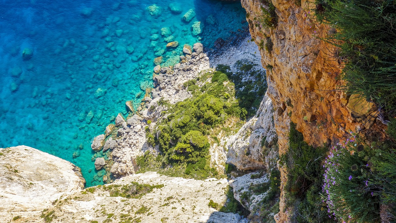 a person standing on top of a cliff next to a body of water, a picture, by Simon Marmion, shutterstock, fine art, greece, high angle vertical, details and vivid colors, detailed hd