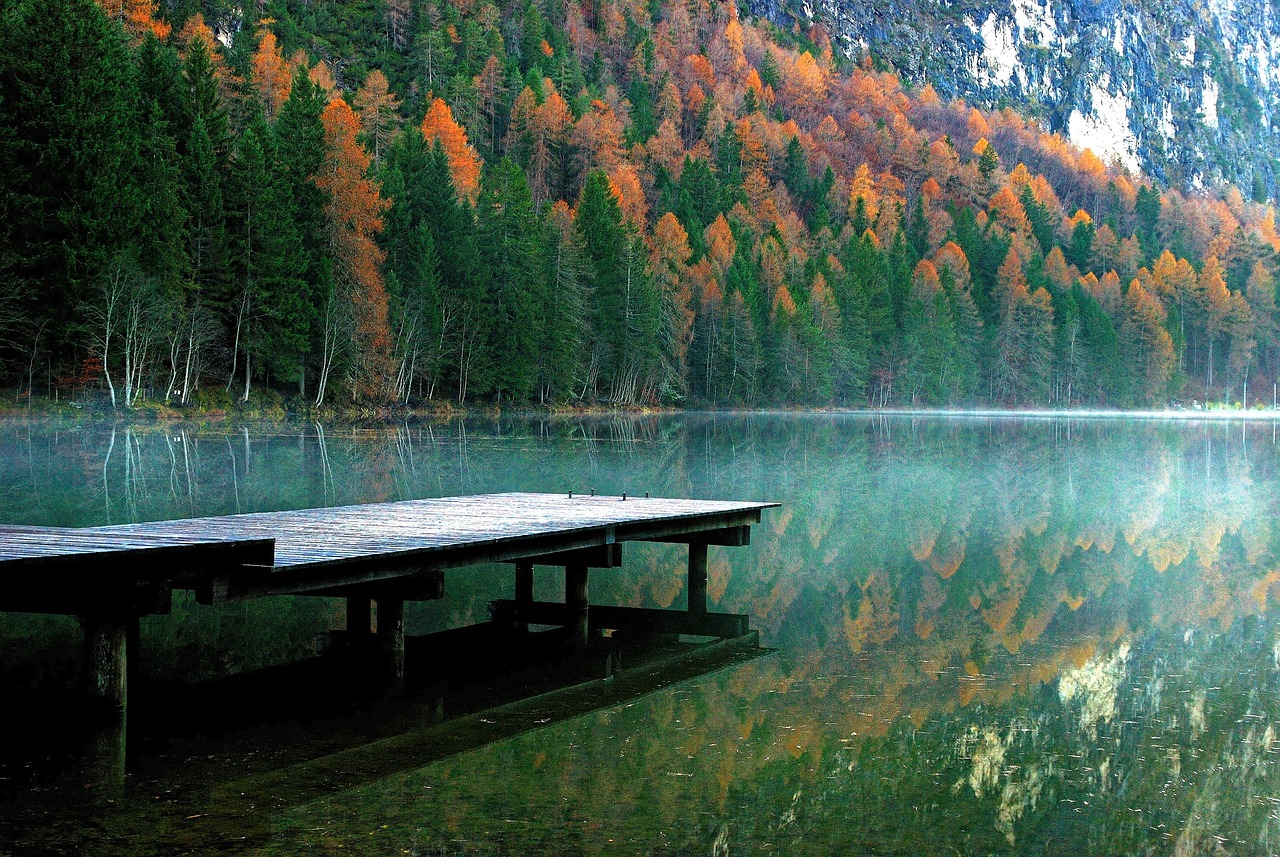 a wooden dock sitting on top of a lake next to a forest, a picture, by Armin Baumgarten, soothing colors, italy, wallpaper - 1 0 2 4, november