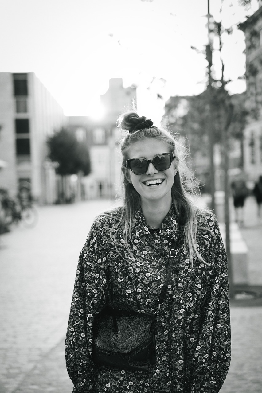 a black and white photo of a woman wearing sunglasses, by Caroline Mytinger, unsplash, happy smiling, in town, topknot, marthe jonkers