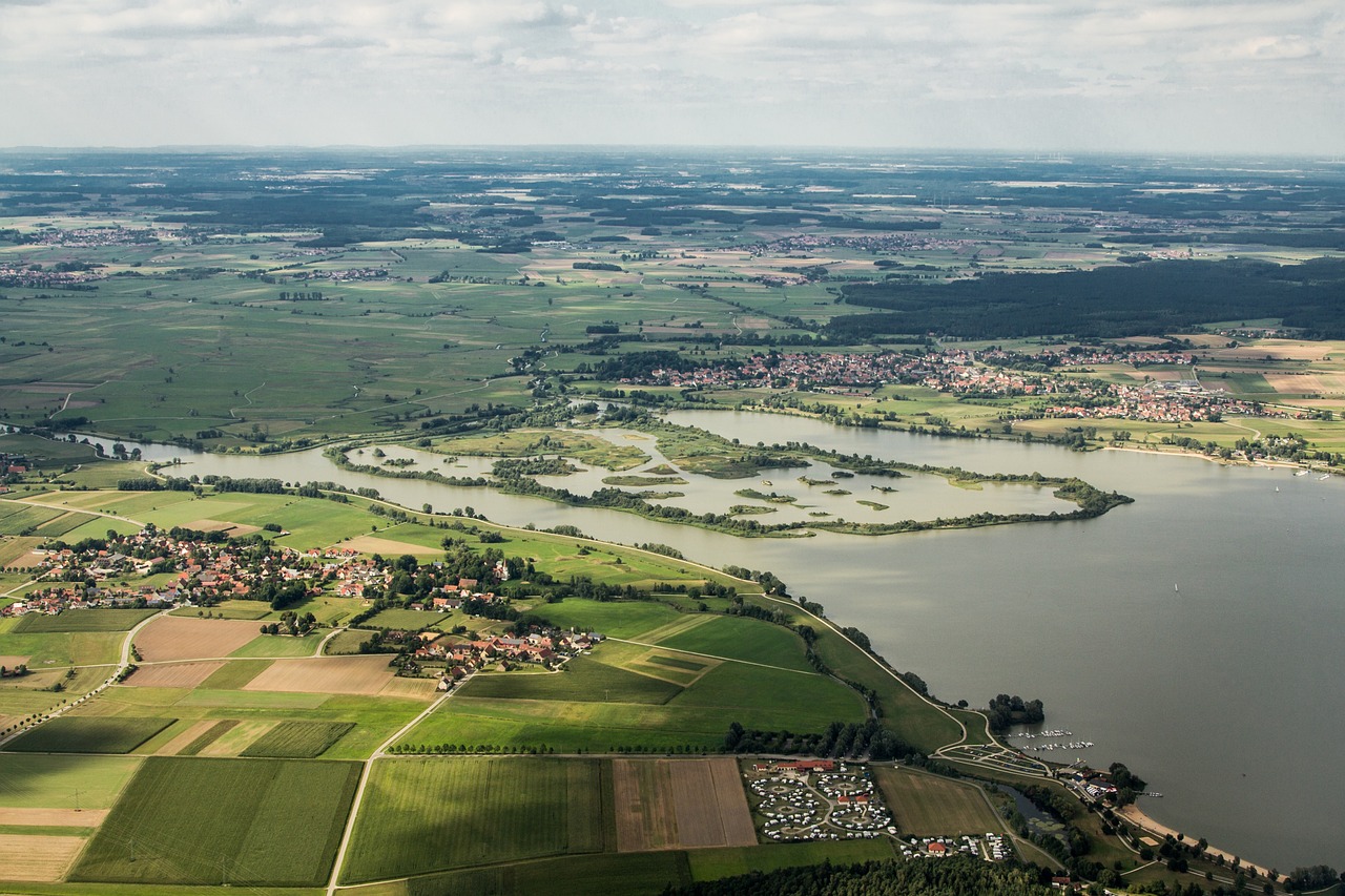 an aerial view of a large body of water, by Karl Völker, shutterstock, fields in foreground, flooded, recreation, distant villagescape