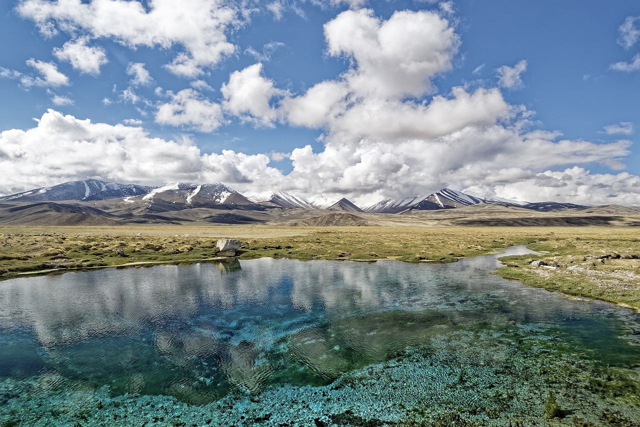 a body of water with mountains in the background, by Andrei Kolkoutine, hurufiyya, lariennechan, perfect spring day with, fantastically beautiful, ponds