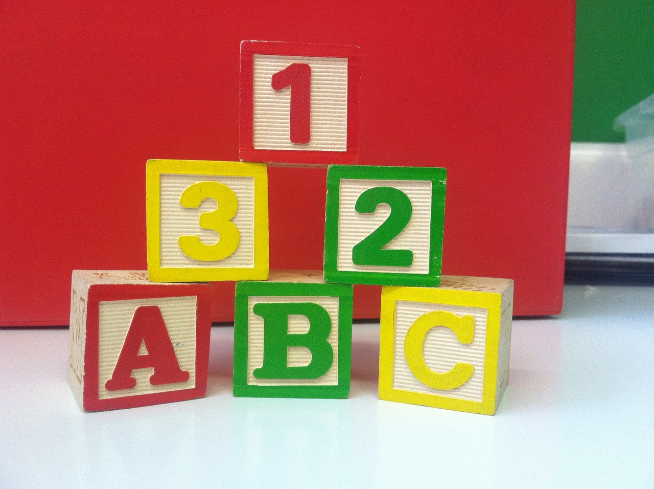a stack of wooden blocks sitting on top of a table, by Alexander Robertson, flickr, letterism, wearing red and yellow clothes, bbc, numerical, a green