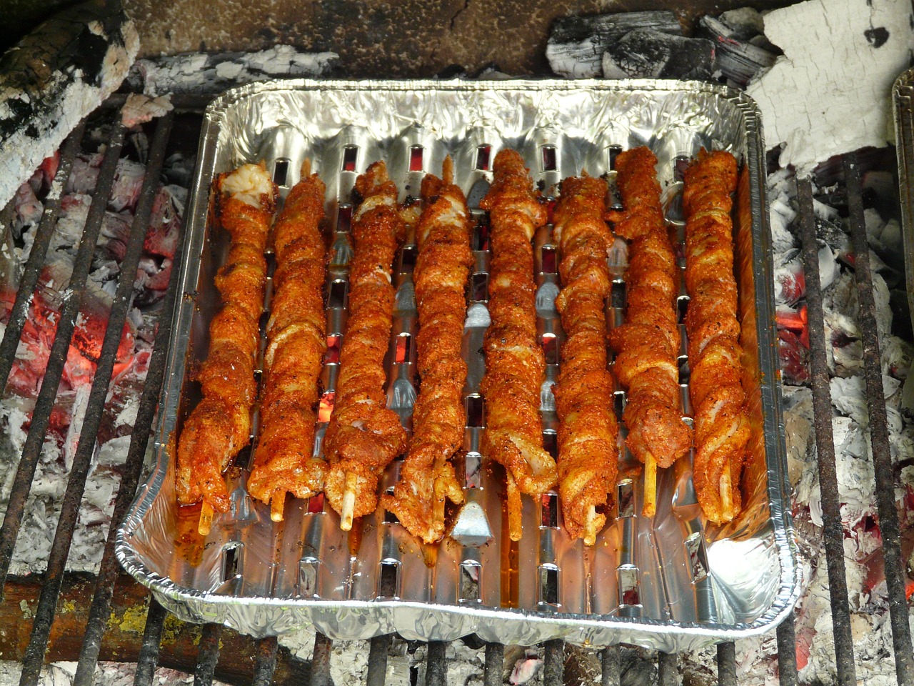 a tray of chicken skewers cooking on a grill, by Ingrida Kadaka, flickr, hurufiyya, devils horns, camp, bacon, year 2134