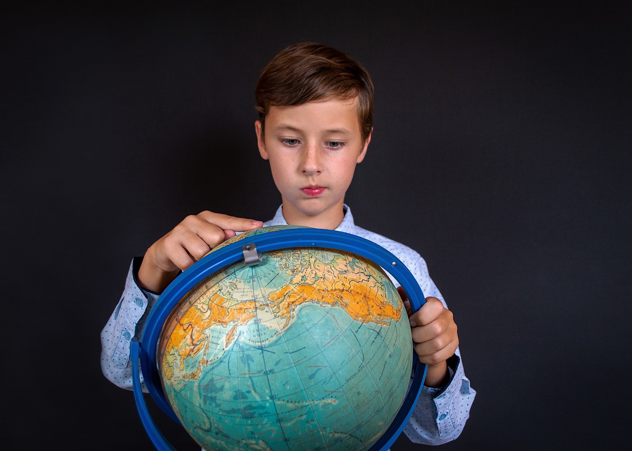 a young boy holding a globe in front of his face, a colorized photo, professional model, well-groomed model, product introduction photo, concentrated