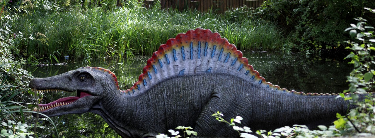 a statue of a dinosaur standing next to a body of water, spines, tetrachromacy, ap photo, top - side view