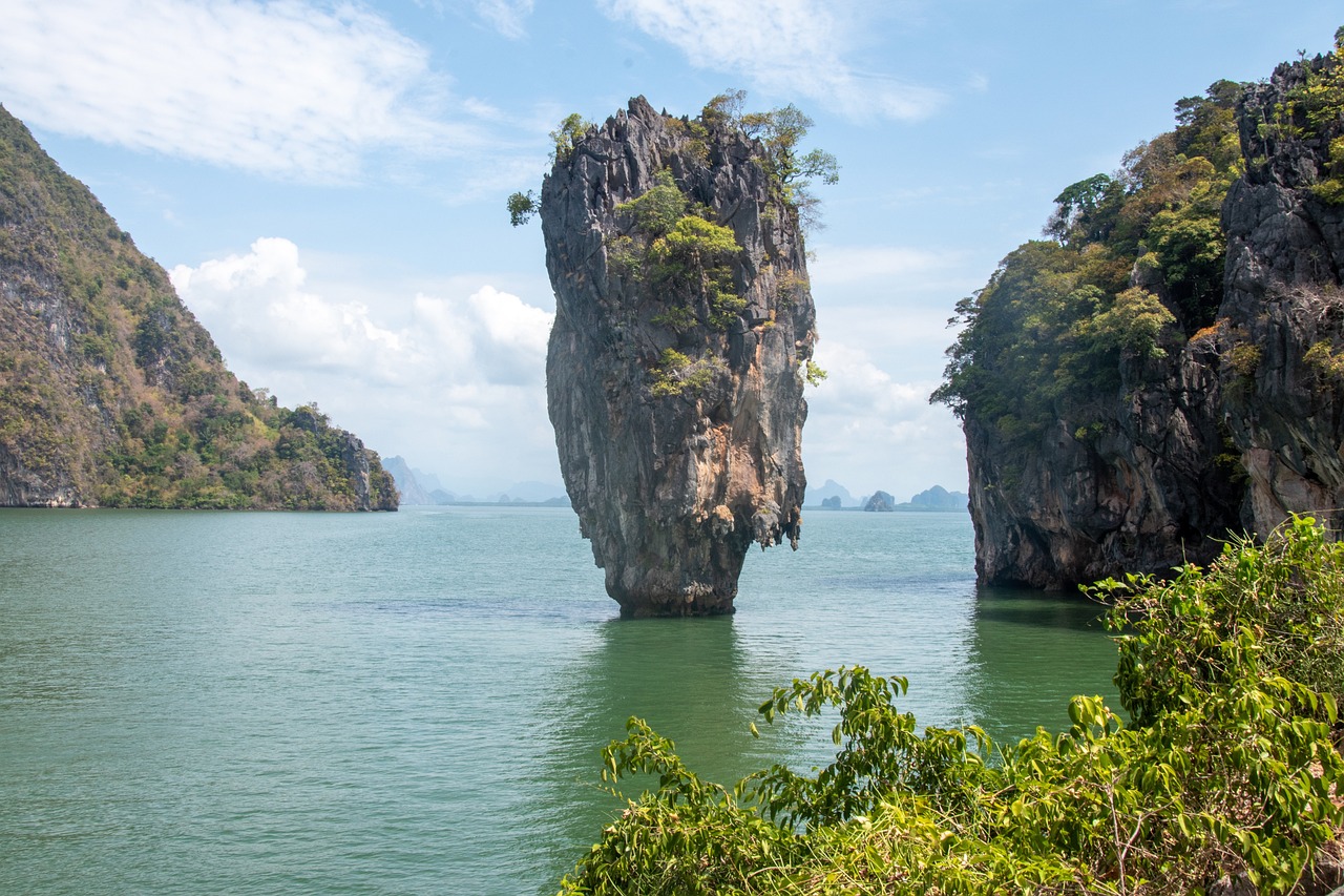 a large rock in the middle of a body of water, a picture, by Richard Carline, shutterstock, thailand, tall columns, trees growing on its body, flying islands