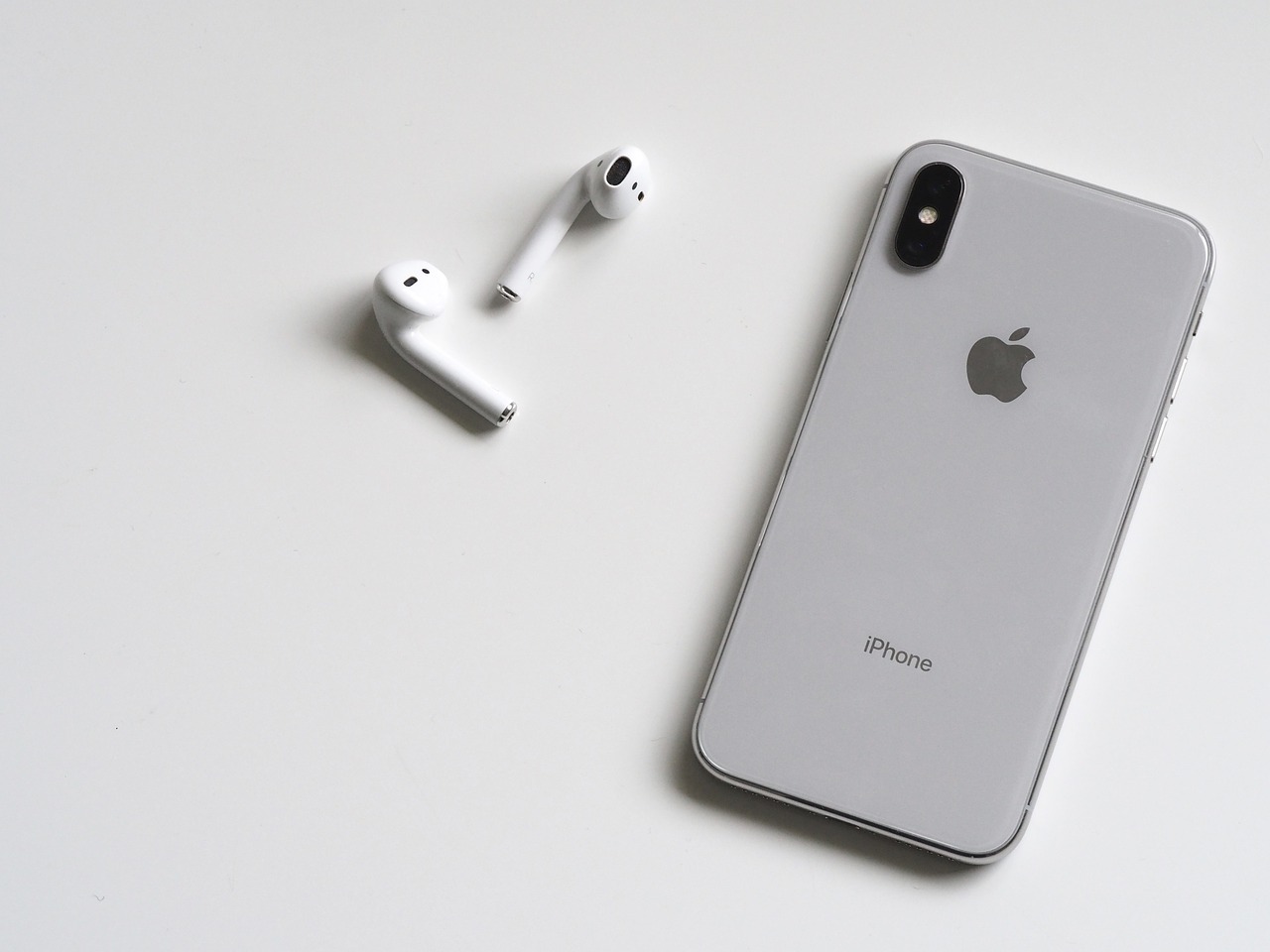 an iphone sitting on top of a table next to a pair of headphones, minimalism, airpods, black on white background, grey and silver, apple - store