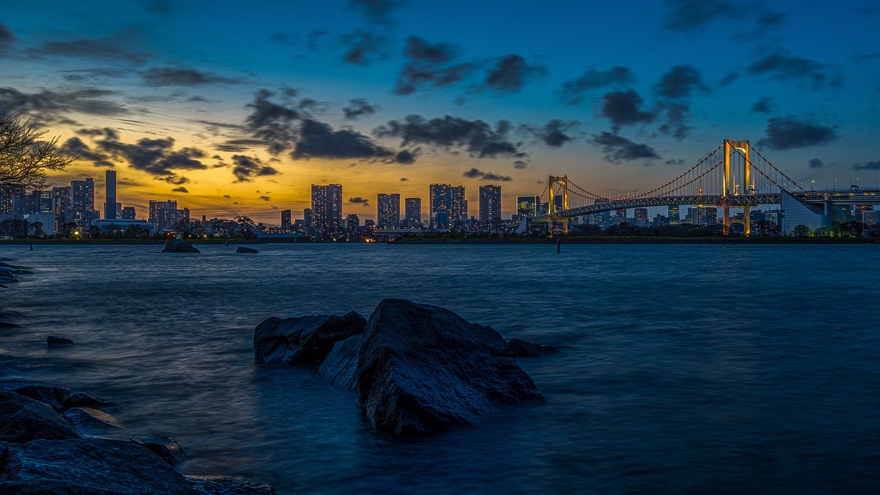 a large body of water with a bridge in the background, a picture, unsplash, sōsaku hanga, vista of a city at sunset, blue and gold, marble!! (eos 5ds r, nightfall