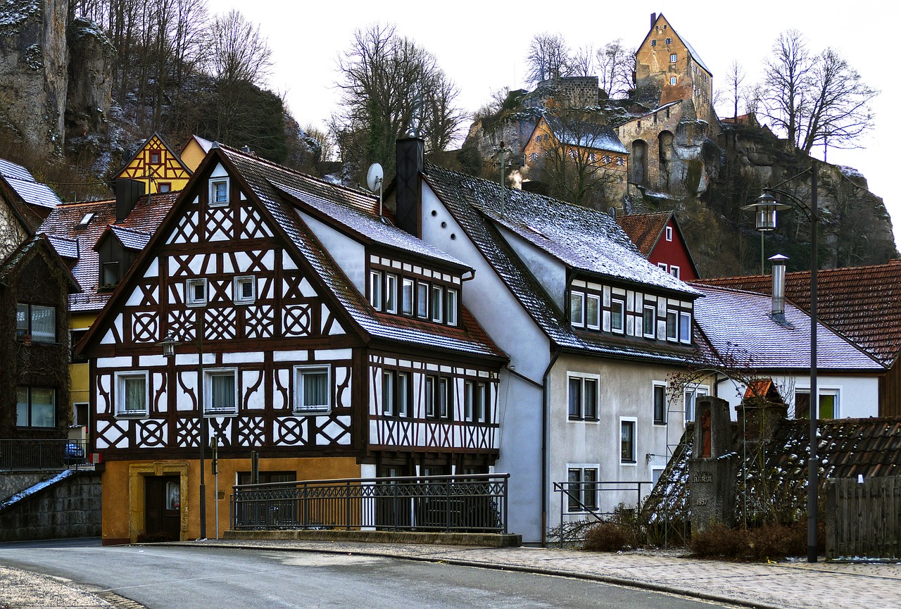 a couple of buildings sitting on the side of a road, by Karl Pümpin, flickr, renaissance, peaked wooden roofs, magical castle school on a hill, february), germany