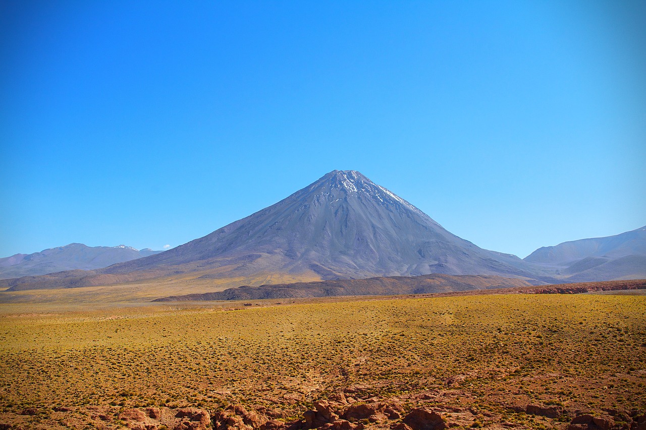 a large mountain in the middle of a desert, a photo, chile, steppe background, blue sky, in a dusty red desert