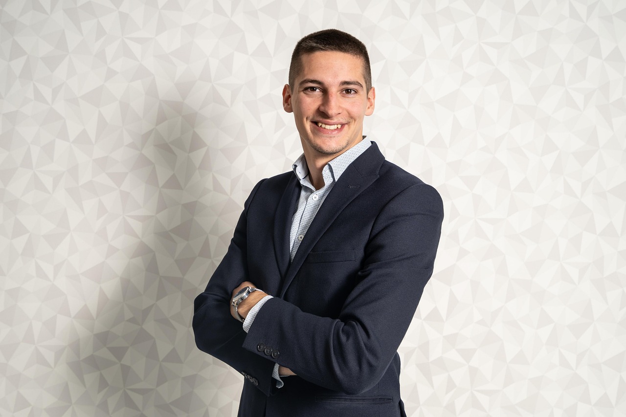 a man in a suit standing with his arms crossed, by Micha Klein, max verstappen, headshot profile picture, edin durmisevic, on grey background