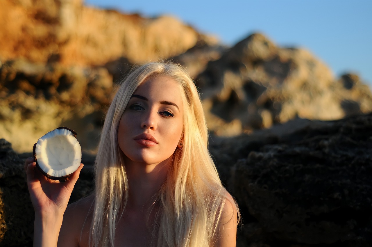 a beautiful blond woman holding a coconut in her hand, inspired by Károly Lotz, tumblr, very pale skin, on a rock, backlit beautiful face, ava max