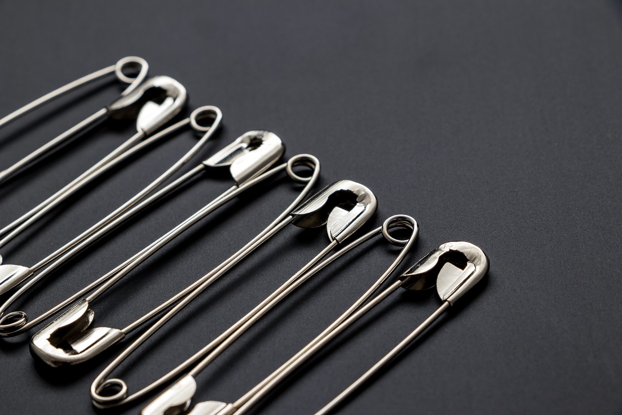 a group of safety pins sitting on top of a table, a stock photo, by Jan Kupecký, process art, high detail product photo, black tie, professional product photo, spoon