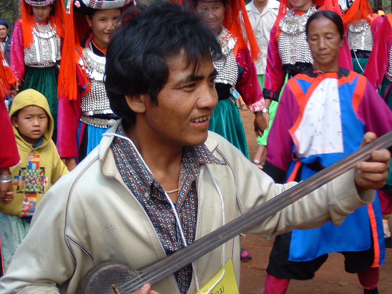 a man holding a guitar in front of a group of people, flickr, dau-al-set, laos, very detaile, sichuan, bassist