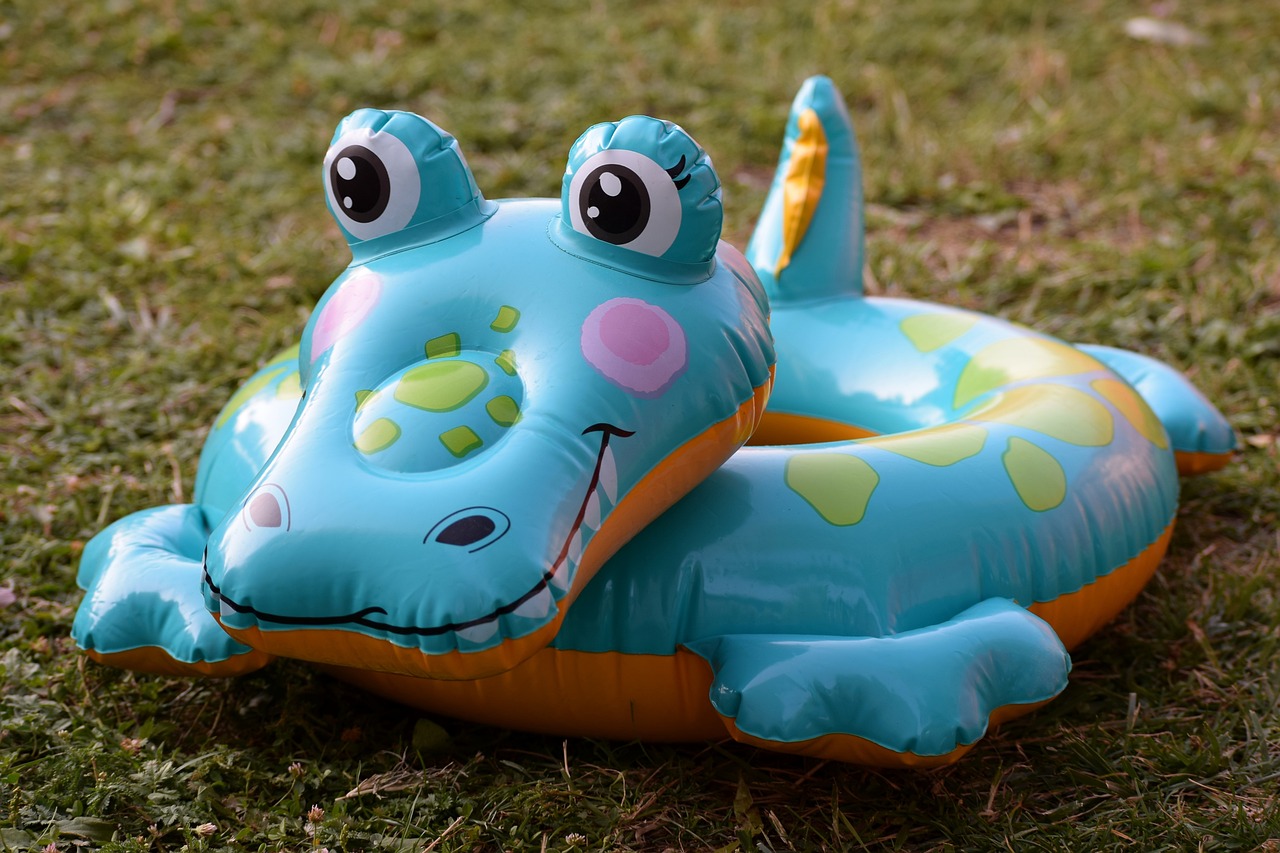 a blue and orange inflatable toy sitting in the grass, inspired by Abidin Dino, alligators, closeup photo, pool, round