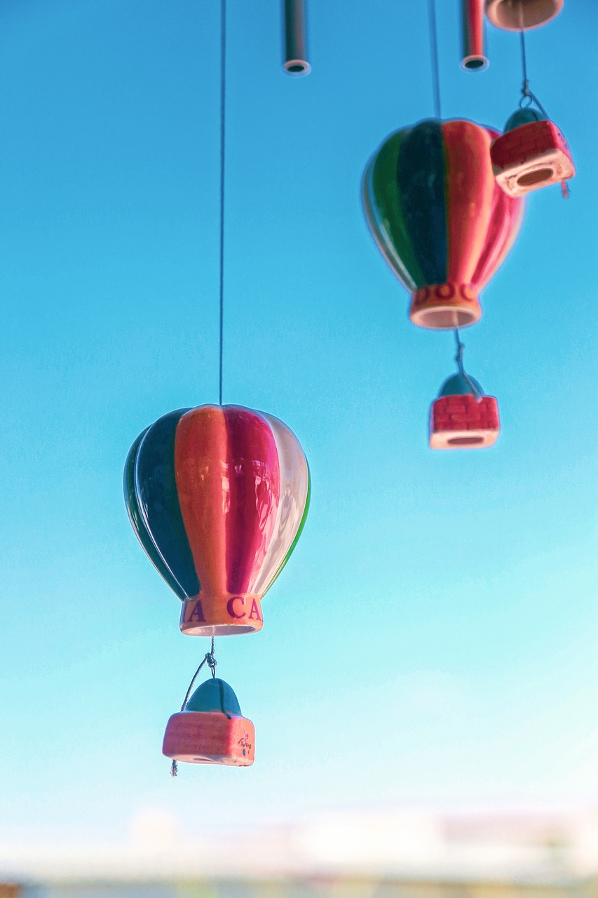 a couple of hot air balloons that are in the air, unsplash, kinetic art, in retro colors, suspended in air, on a sunny day, closeup photograph