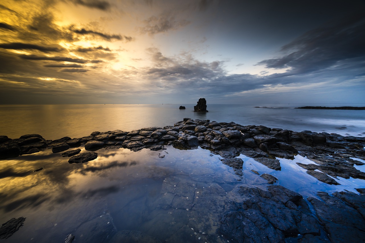 a body of water surrounded by rocks under a cloudy sky, a picture, by Andrew Geddes, beautiful rtx reflections, beautiful sea landscapes, morning atmosphere, covered with liquid tar. dslr