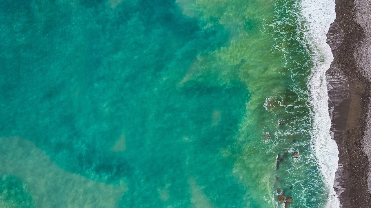 a large body of water next to a beach, a screenshot, pexels, conceptual art, teal, background image, wide aerial shot, maui