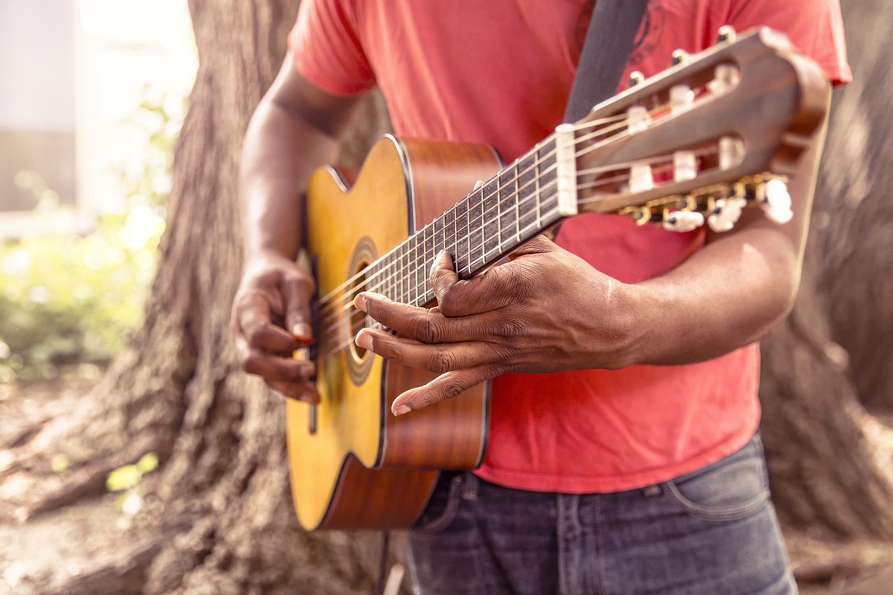 a man holding a guitar in front of a tree, by david rubín, pexels, istockphoto, superior detail, mulato, plays music