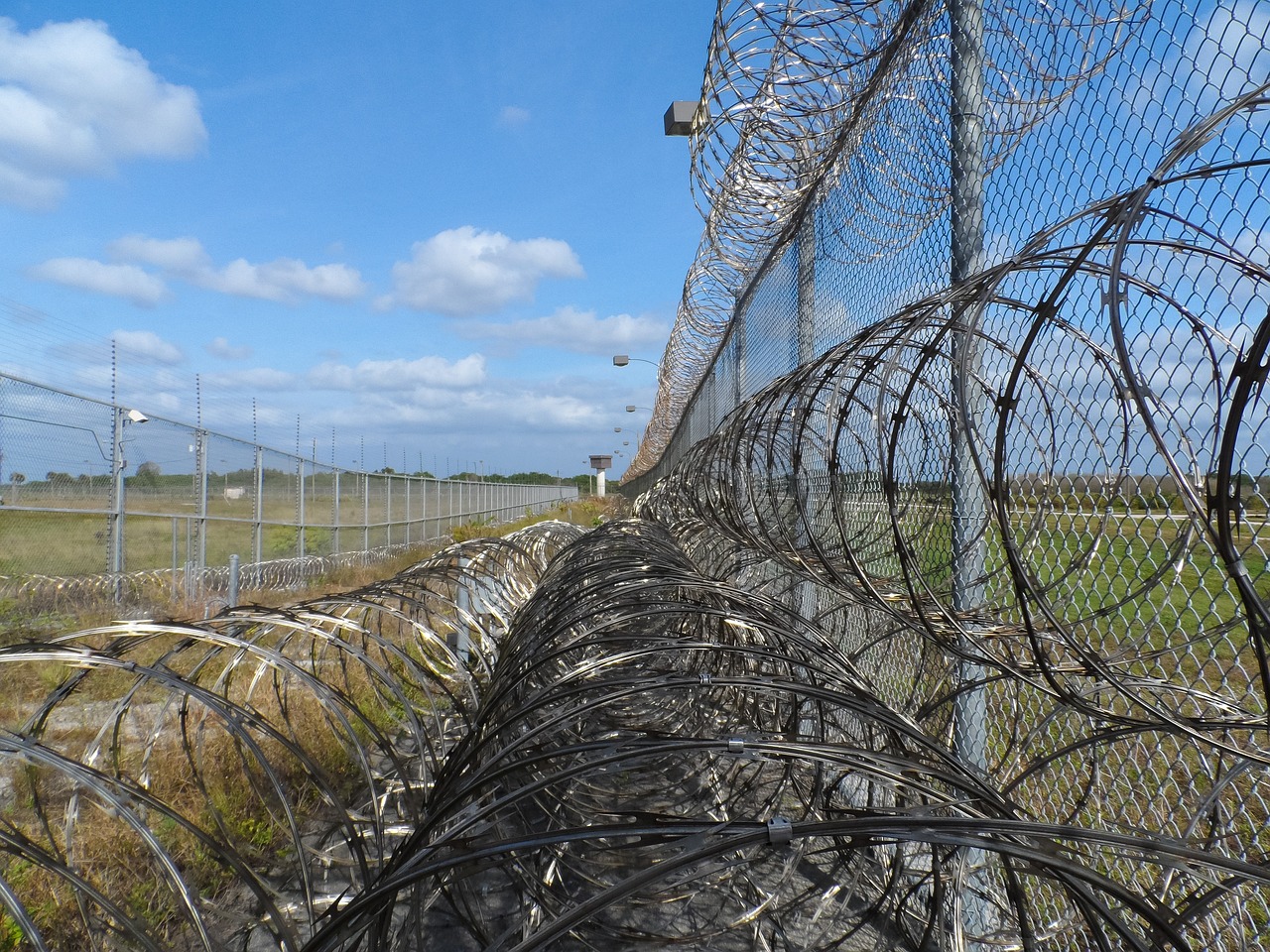 a barbed wire fence next to a field, by Adam Manyoki, flickr, conceptual art, in a prison cell, terminal, half turned around, from wikipedia