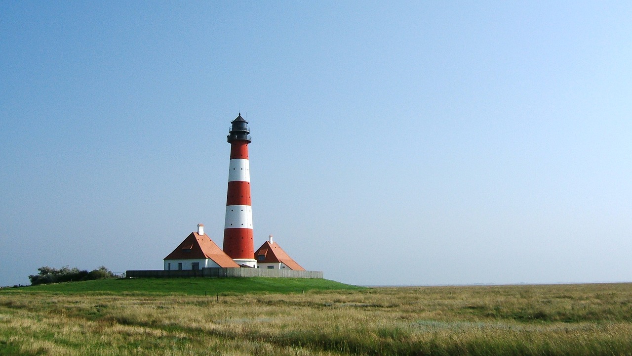 a red and white lighthouse sitting on top of a lush green field, a picture, by Jan Asselijn, chimney, coast, wikipedia, clear and sunny