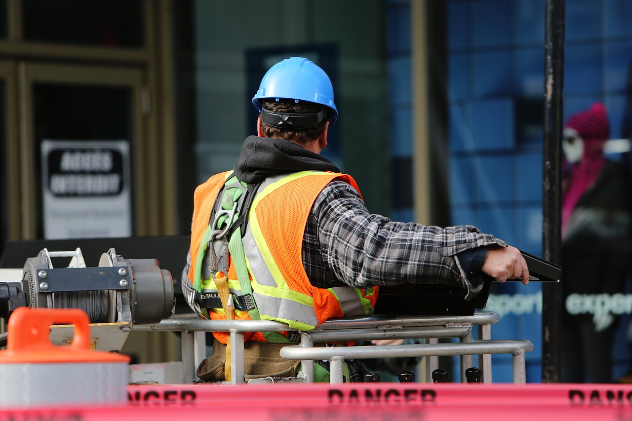 a construction worker wearing a safety vest and a hard hat, a photo, by Tom Carapic, blog-photo, sitting, his back is turned, afp