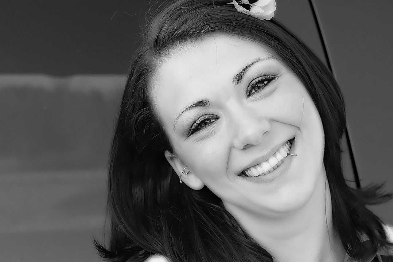 a black and white photo of a woman holding an umbrella, a black and white photo, pixabay, big smile white teeth, closeup headshot portrait, young woman in her 20s, devon cady-lee