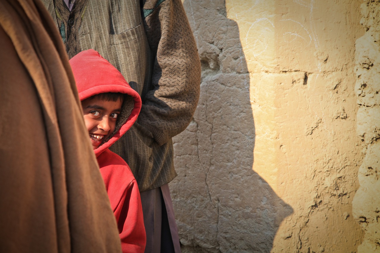 a close up of a person wearing a red hoodie, a picture, by Richard Carline, shutterstock contest winner, 14 yo berber boy, his smile threw shadows, wearing brown robes, young himalayan woman