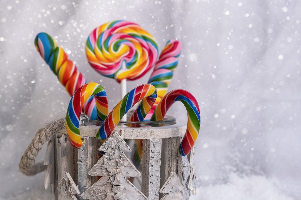 a couple of lollipops sitting on top of a tree stump, a picture, by Kanbun Master, shutterstock, candy canes, rainbow colors, still life with snow, high detail product photo