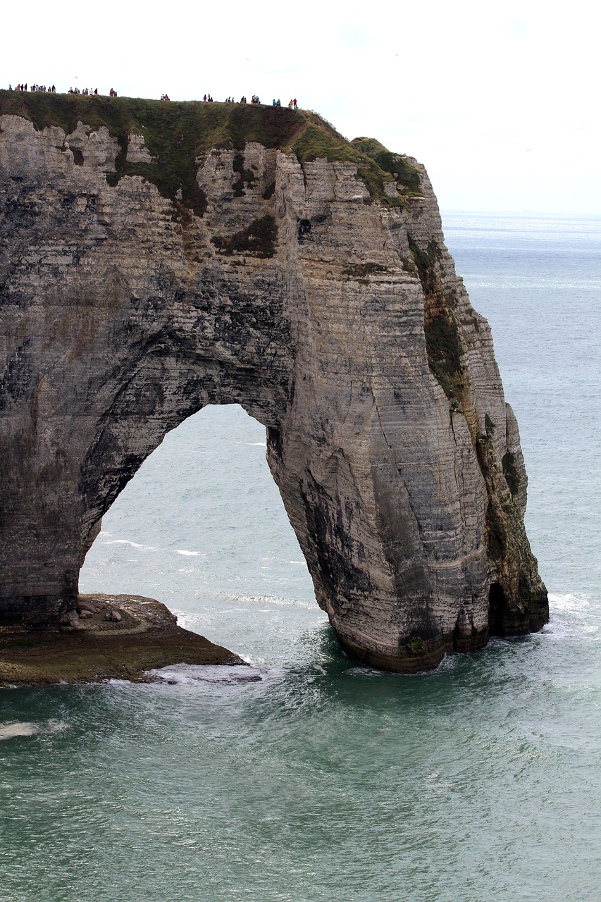 a large rock formation in the middle of the ocean, by François Girardon, pixabay, romanticism, gothic arch frame, over a chalk cliff, northern france, portal opening