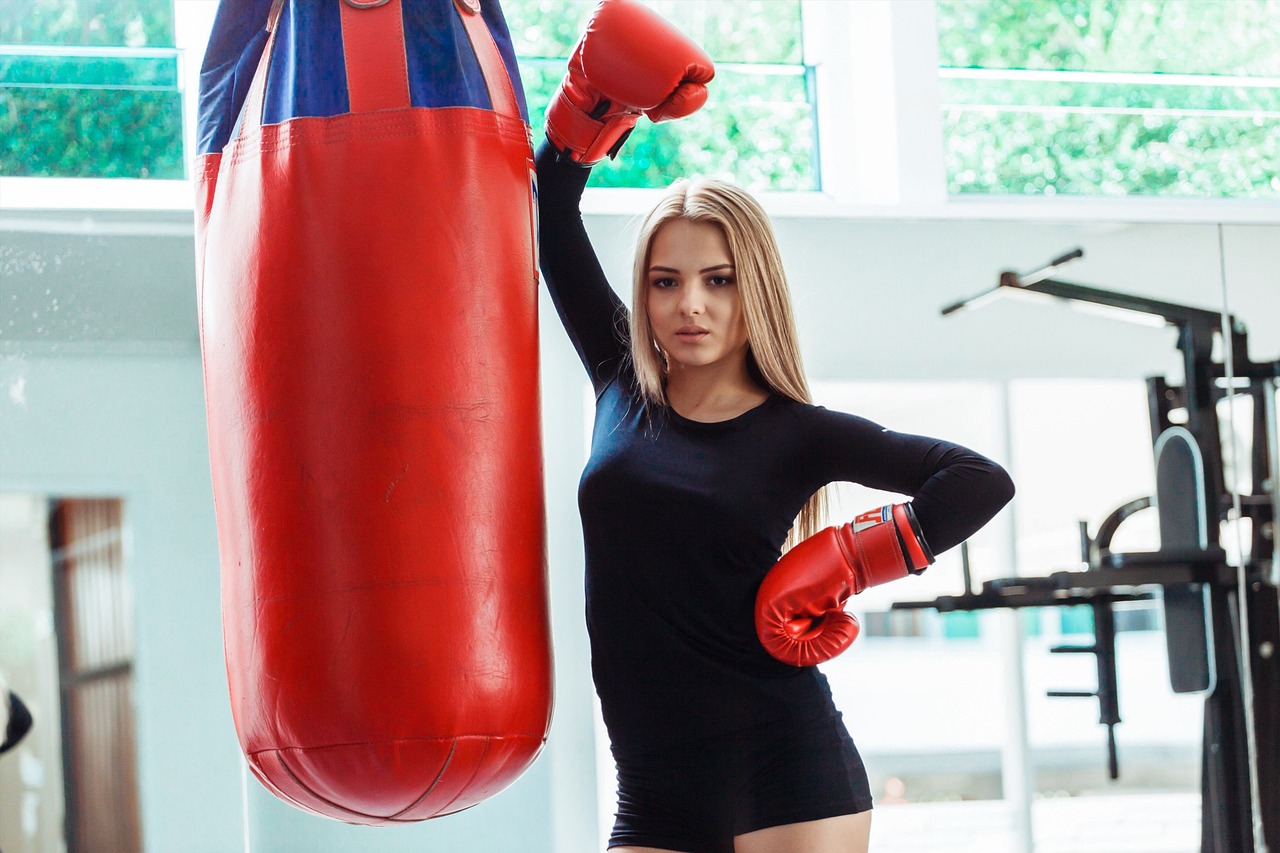 a woman standing next to a punching bag, by Ilya Ostroukhov, shutterstock, with a large breasts, red sport clothing, dasha taran, wearing black tight clothing