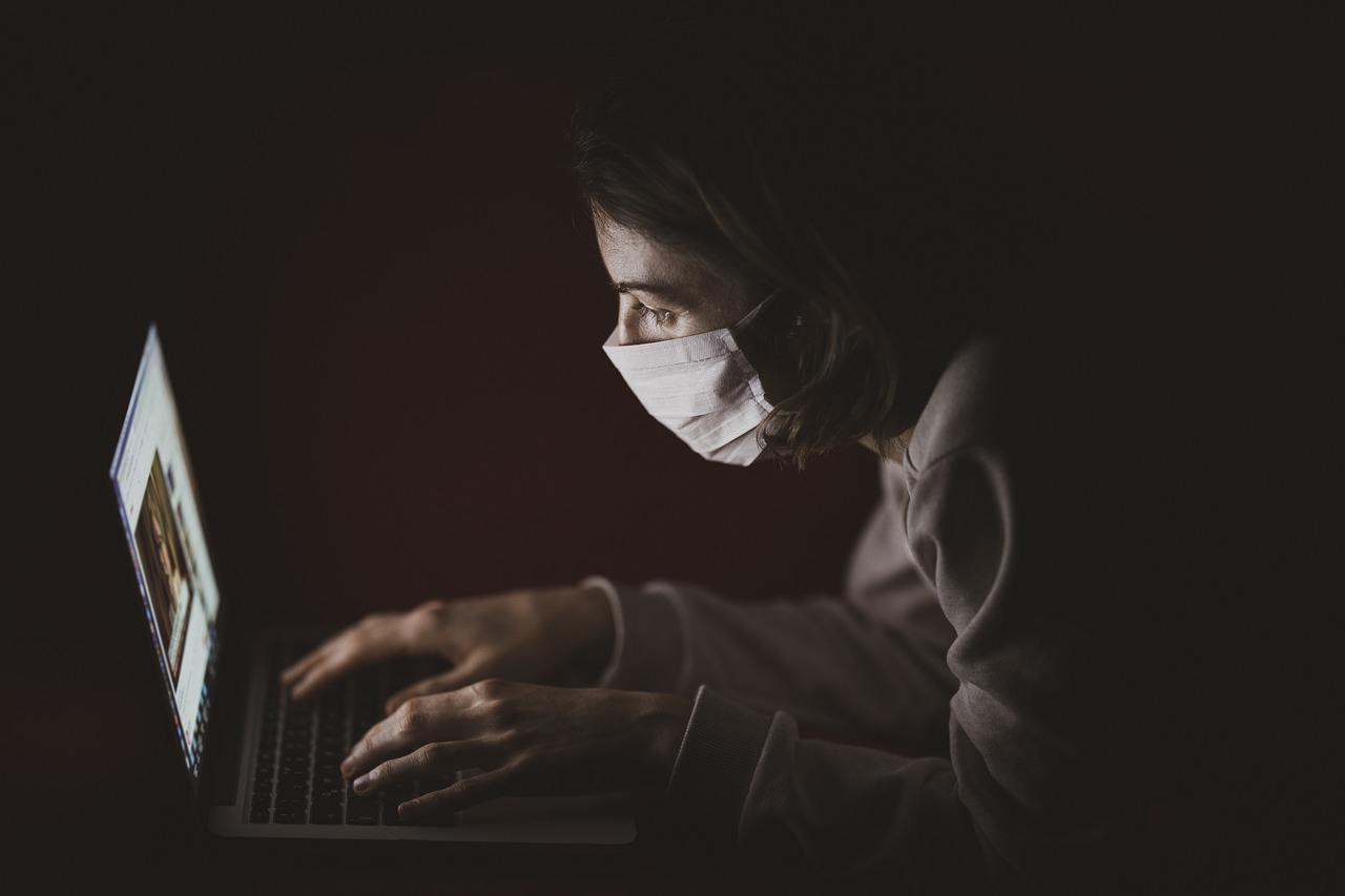 a woman wearing a face mask working on a laptop, a picture, by Emma Andijewska, horror photo, disease, lit from the side, 2d