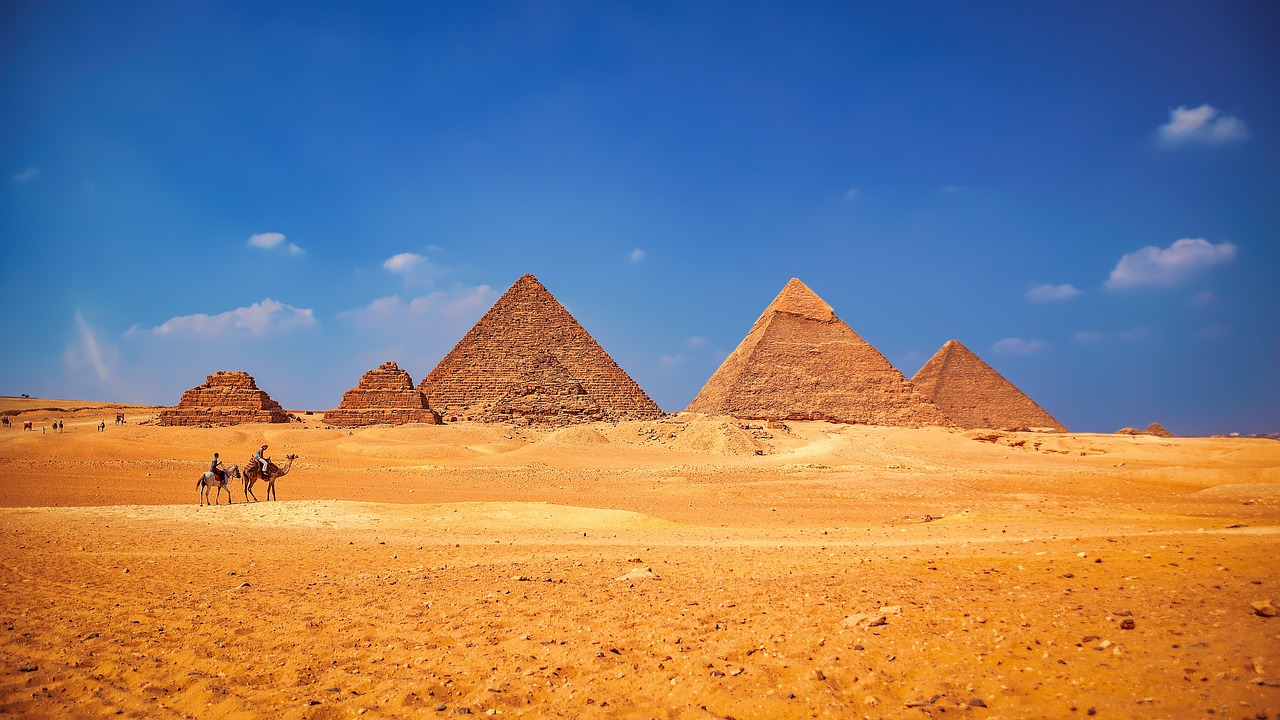 a group of people riding camels in front of the pyramids, egyptian art, shutterstock, panorama of crooked ancient city, shot on a 9.8mm wide angle lens, desert and blue sky, sand piled in corners