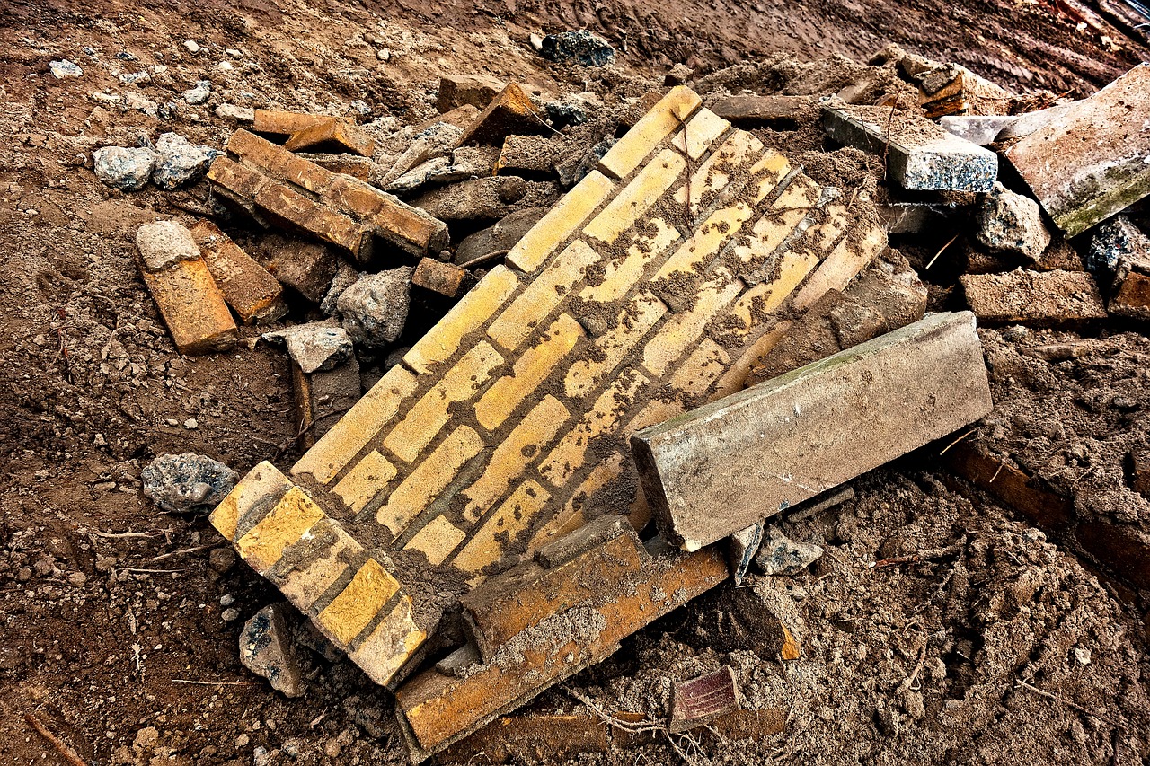 a brick laying on top of a pile of rubble, by Richard Carline, flickr, vibrant but dreary gold, complex layered composition!!, broken road, after a riot