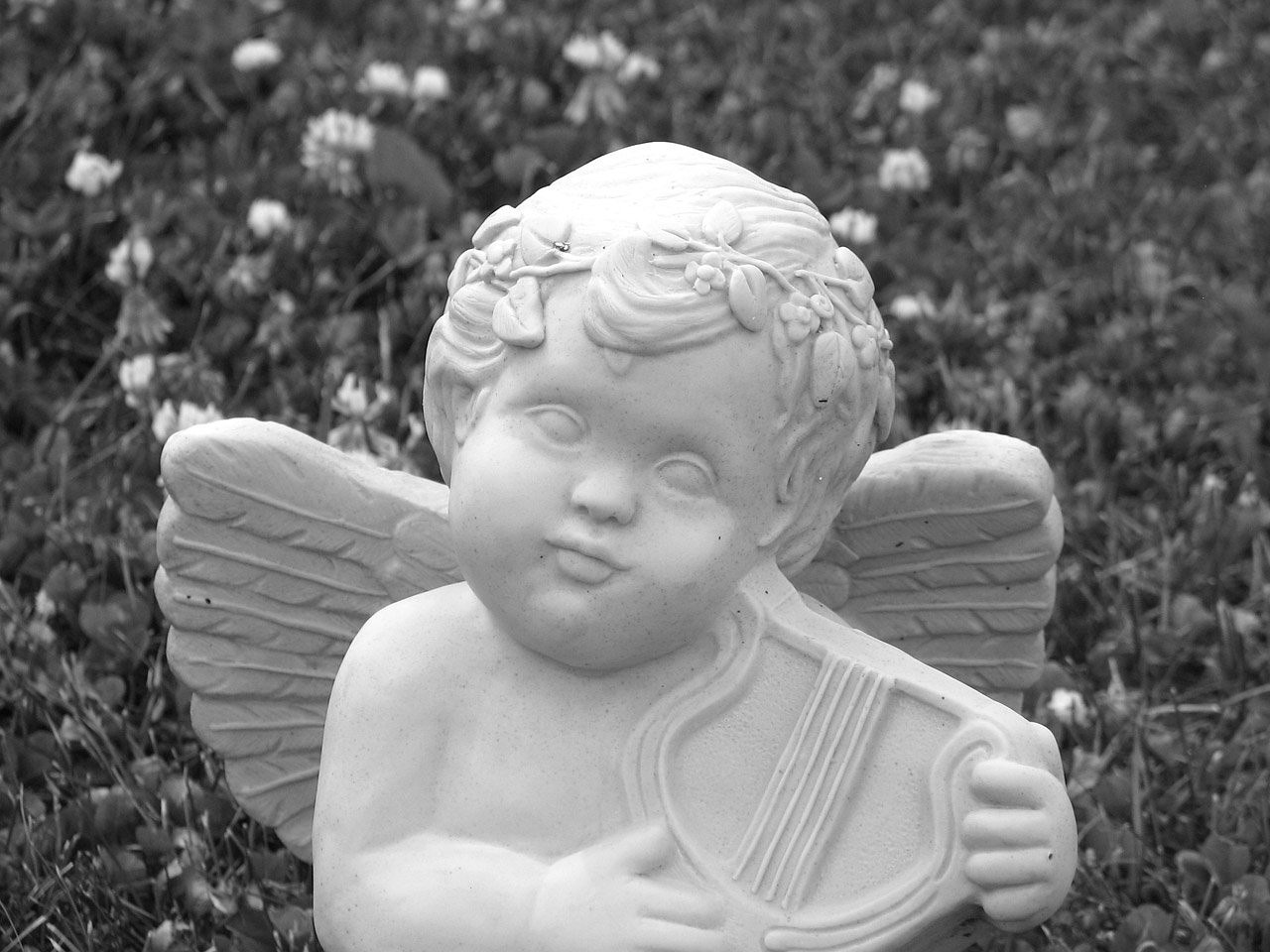 a black and white photo of a statue of a cupid, inspired by Margaret Brundage, pixabay contest winner, focus on the musicians, in the garden, 2000s photo, smiling softly