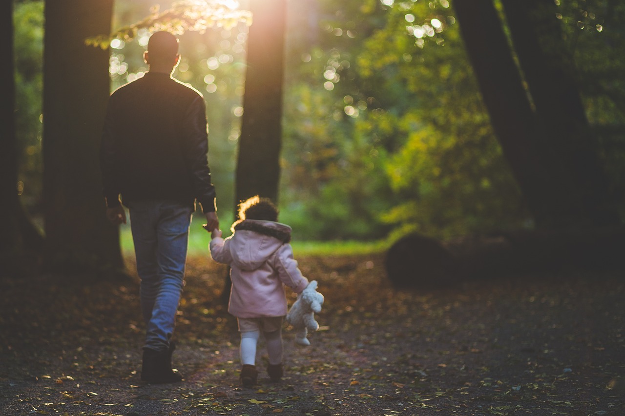 a man and a little girl walking in the woods, by Sebastian Vrancx, pexels, realism, bokeh in the background only, warm sundown, father with child, future activist
