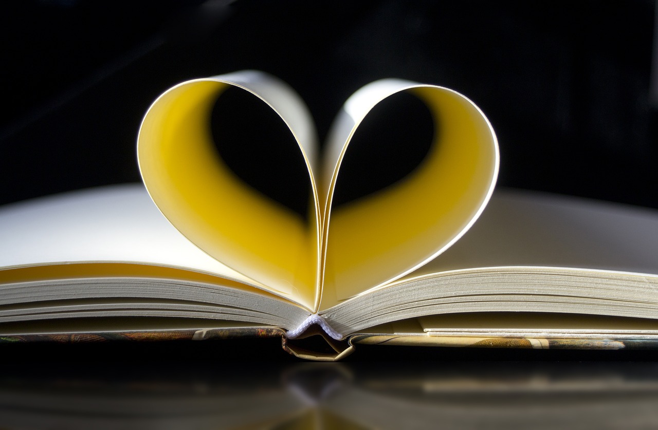 a heart shaped book sitting on top of a table, a picture, by Adam Chmielowski, flowing book pages, on a yellow paper, marketing photo, exquisite and smooth detail