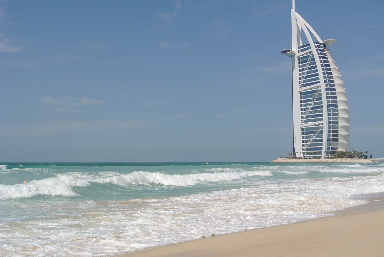 a tall building sitting on top of a beach next to the ocean, a picture, hurufiyya, dubai, banner, beaching, image