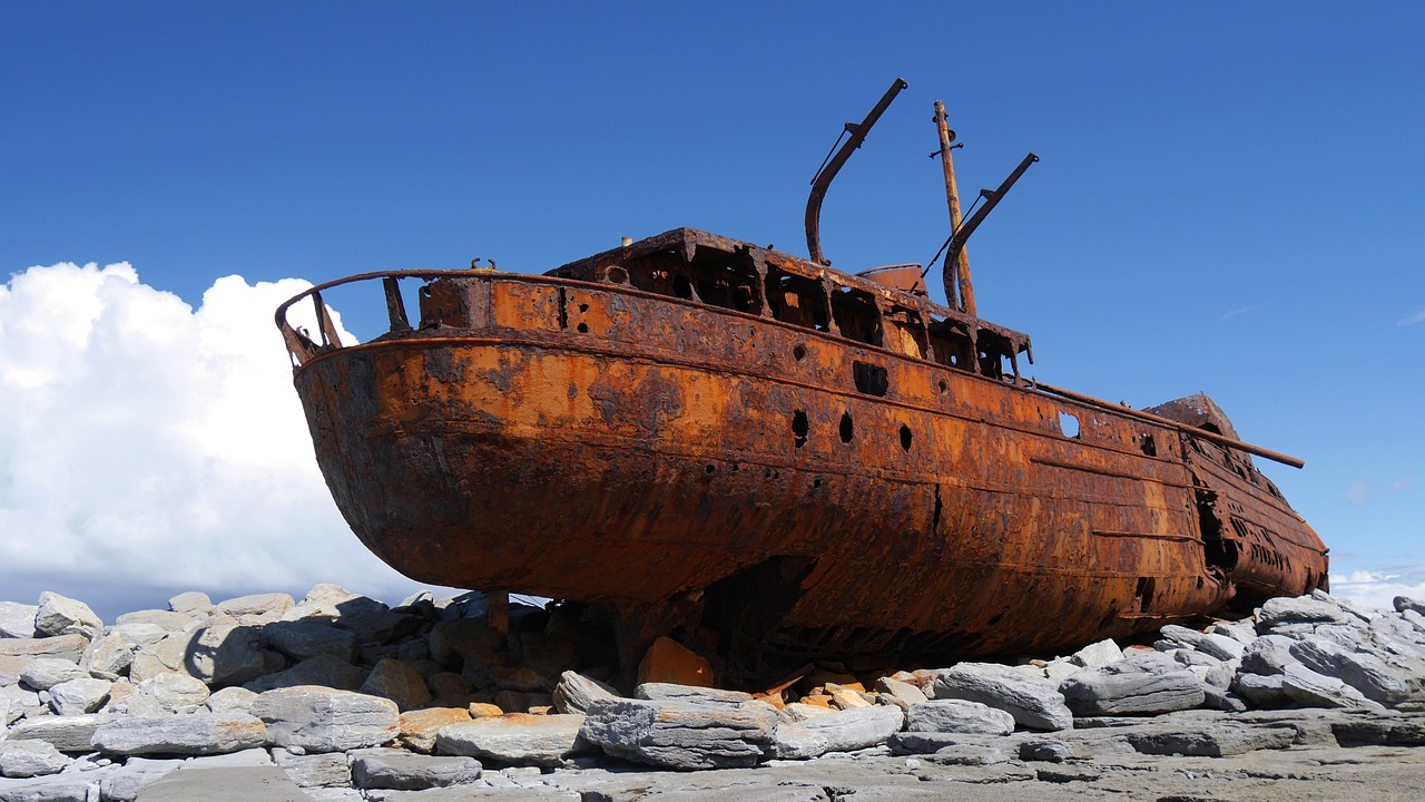 a rusted ship sitting on top of a pile of rocks, manuka, wikimedia, epic and stunning, cracked varnish