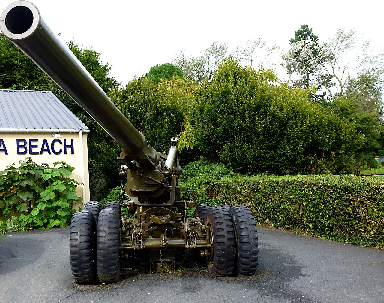a large gun sitting in the middle of a parking lot, by Robert Brackman, flickr, dada, omaha beach, ireland, 2 arms and 2 legs!, breath taking